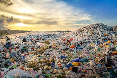 large pile of trash extending into a bright sunset