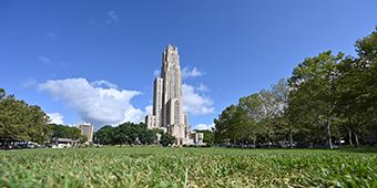 Caethdral of Learning at Pitt as seen behind a long, grassy lawn