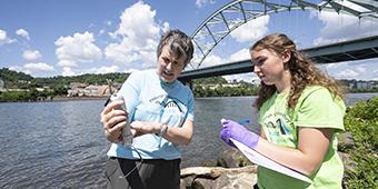 Faculty member doing research along river with student