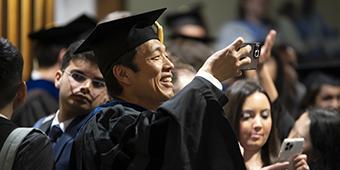 Engineering graduate taking phone selfie during commencement