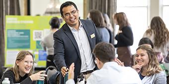 student attendees being greeted by faculty member  at tables during Sustainanbility Awards event