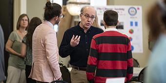 faculty member talking with two students during research showcase