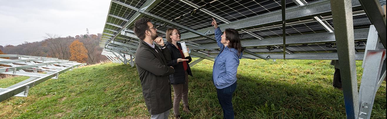 three people looking at underside of solar array panels