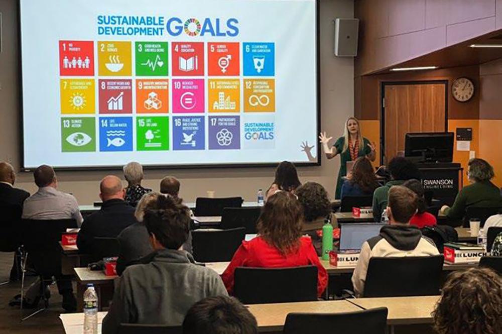 MCSI staff presenting on Sustainable Development Goals in front of gathered students